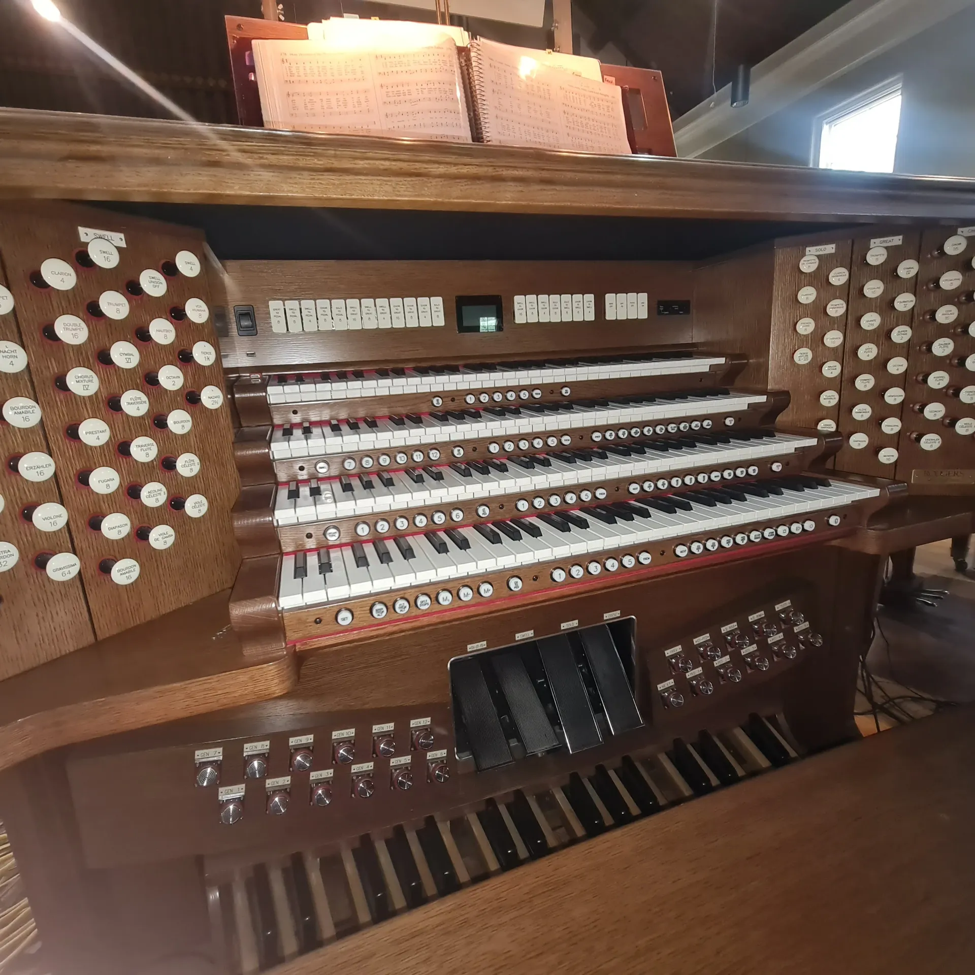 White grand piano in a bright room, with a matching stool, a white couch, and a mirror.