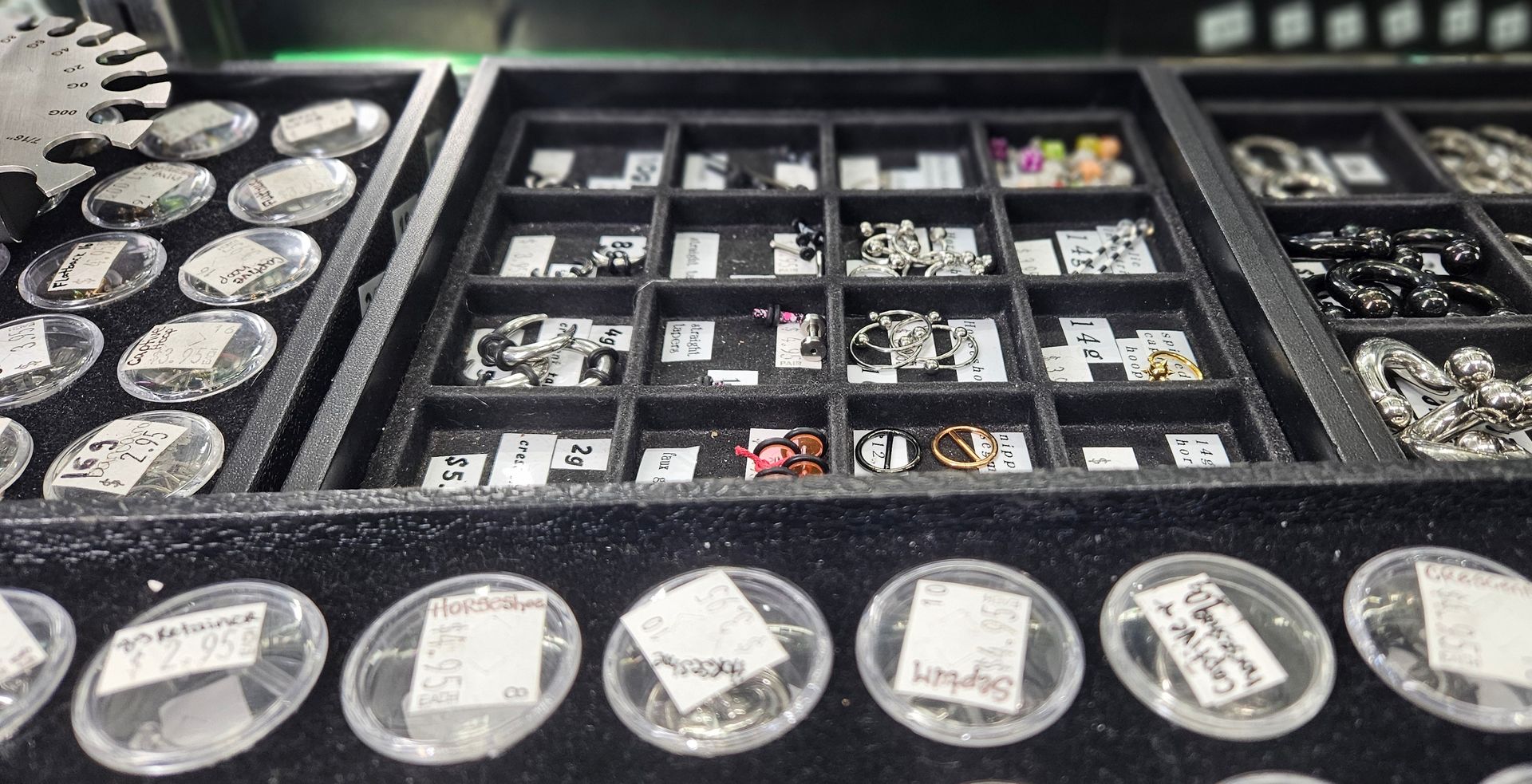 A look into the jewelry case displaying four trays of various gauges of studs, rings, retainers and other body decor.