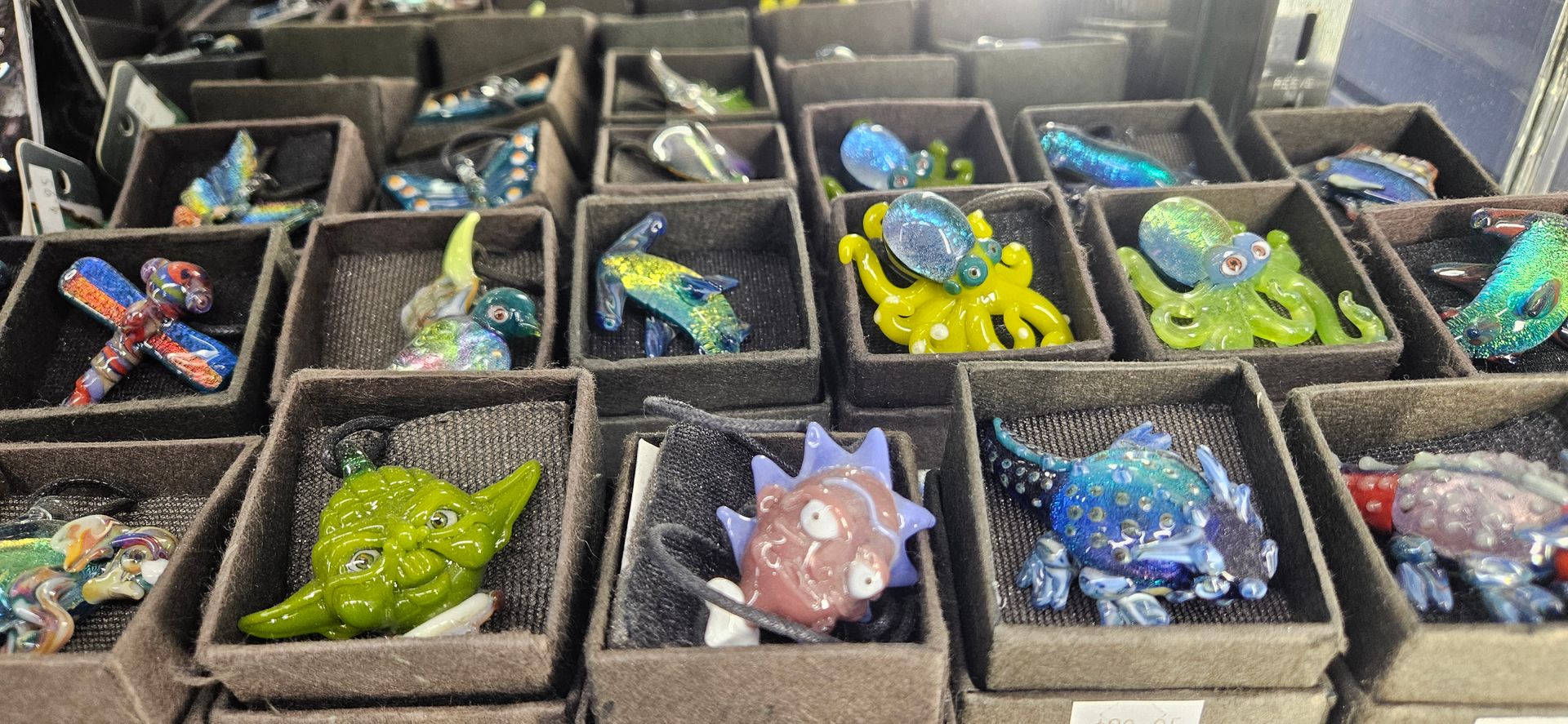 An up close look at several hand-made glass pendants. Characters like Yoda and Rick sit beside beautiful aquatic creatures.