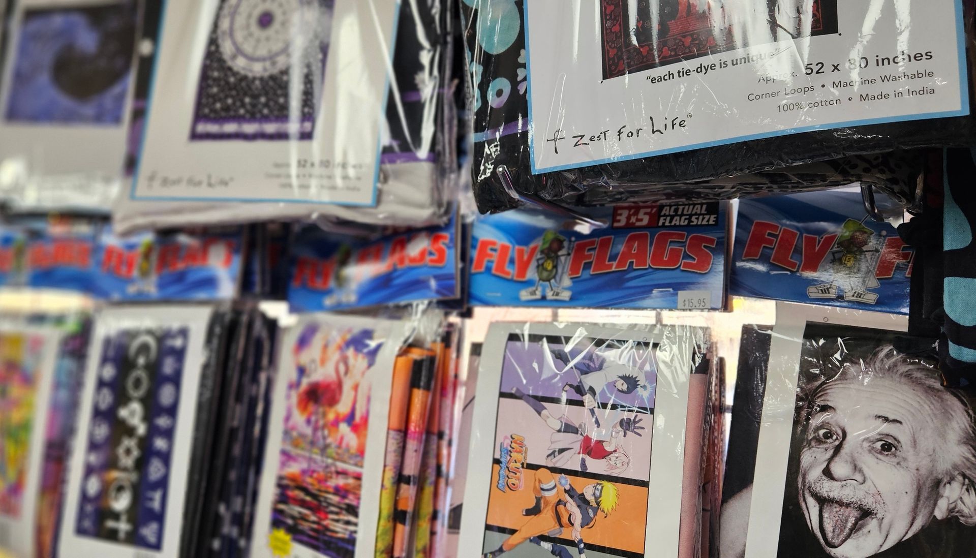 A variety of Fly Flags and tapestries on display, featuring Albert Einstein, anime and other imagery.