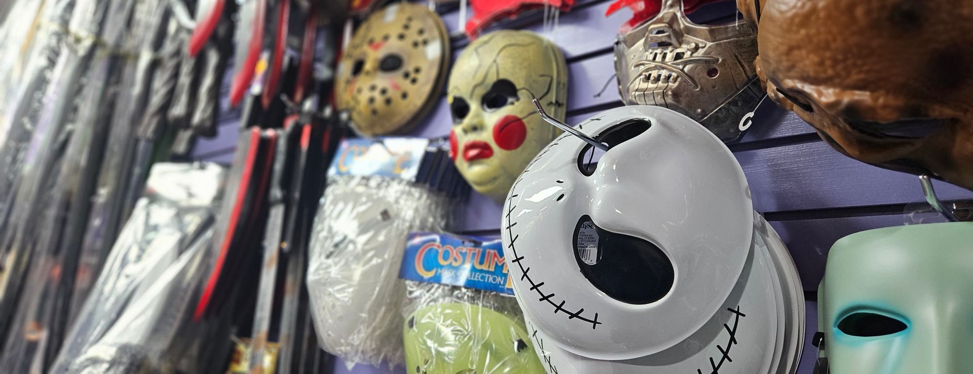 A wall of masks on display. Jack Skellington, Jason and Annabelle the horror doll.