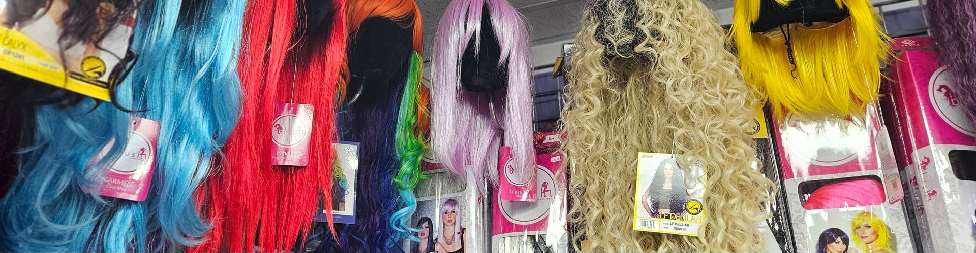 Several wigs on display, some bright and party colored and others beautiful and natural.