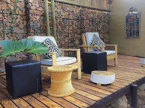 A wooden deck with chairs , tables and ottomans on it.