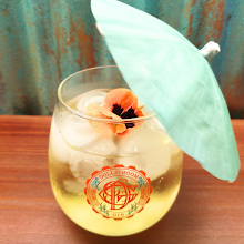 A glass of yellow liquid with ice and a flower in it