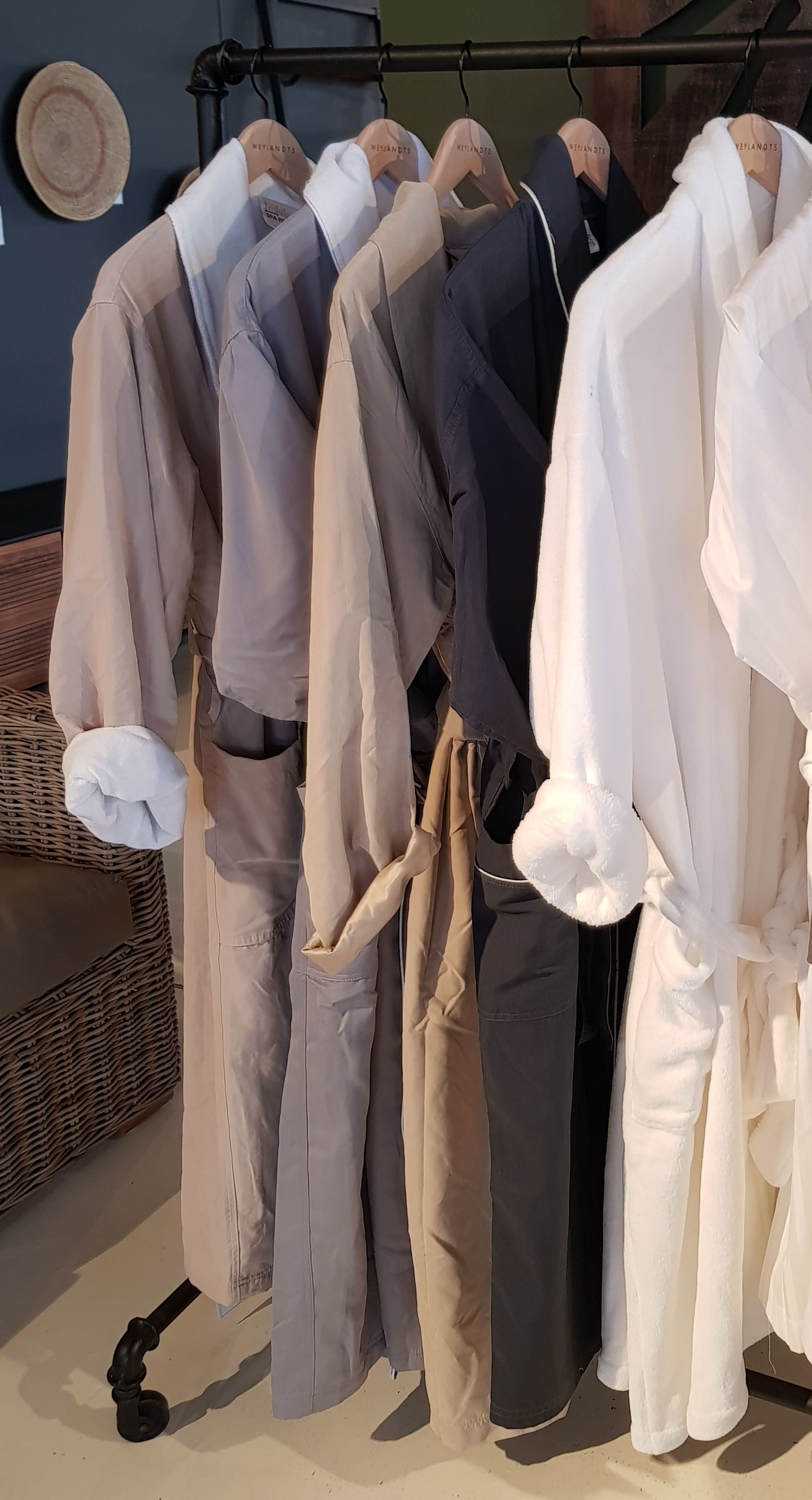A row of bathrobes hanging on a rack in a room.