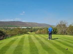 A man is standing on a golf course holding a golf club.