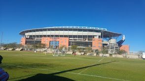 A large stadium with a soccer field in front of it.