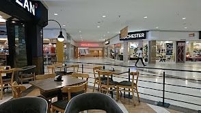 A restaurant in a shopping mall with tables and chairs.