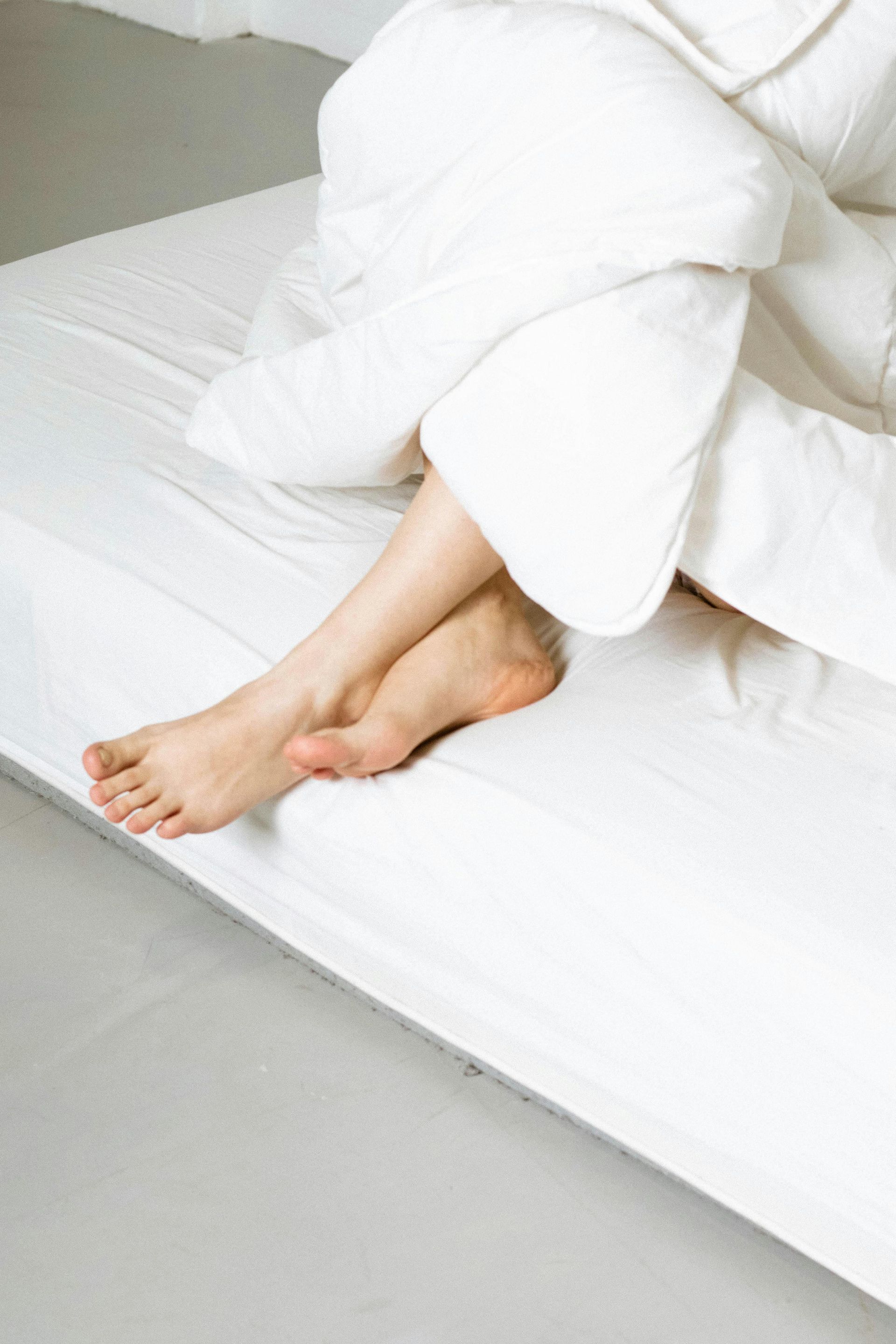 A person is sitting on a bed with their legs crossed.