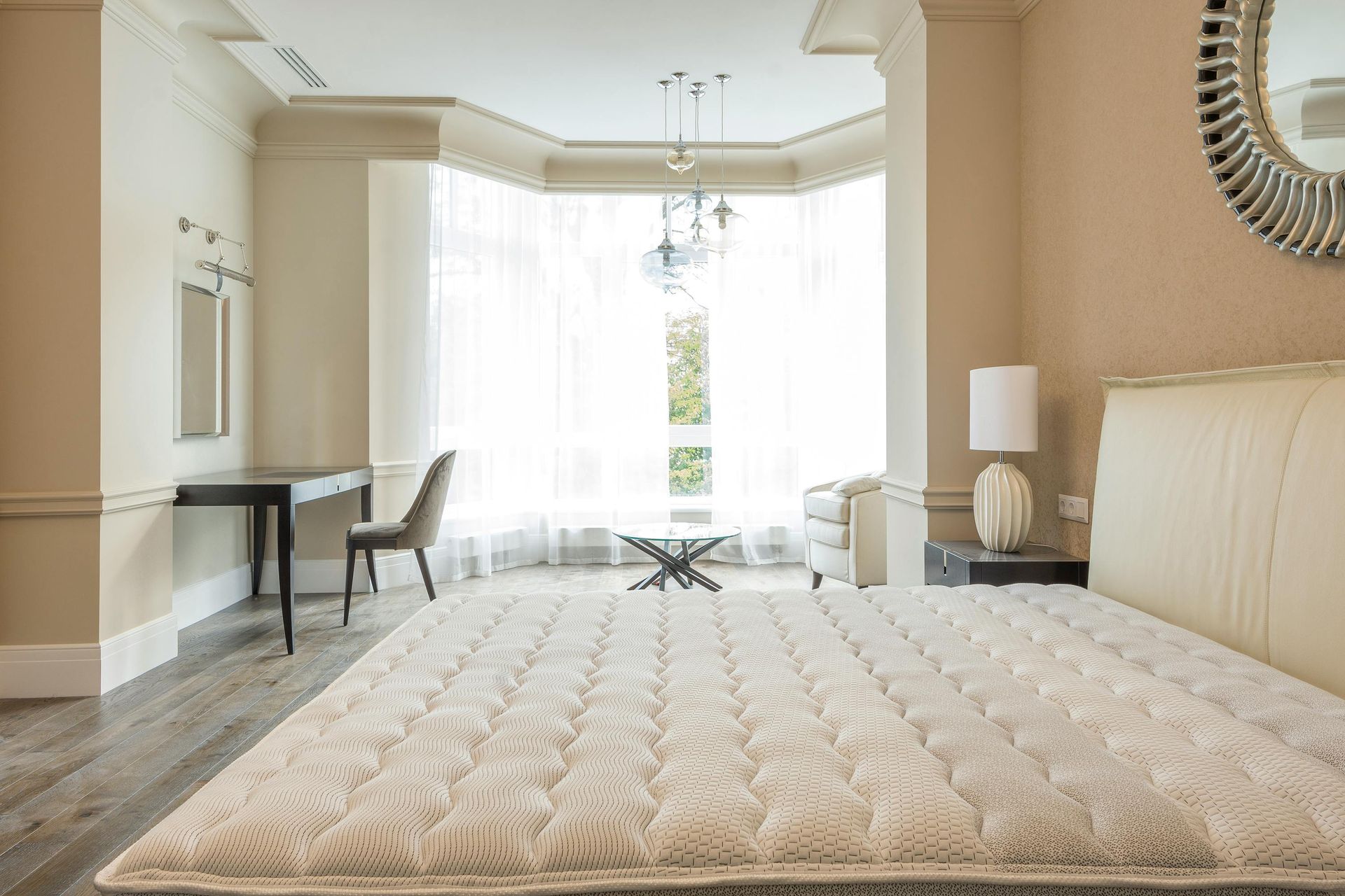 A bed with white sheets and pillows in a bedroom next to a window.