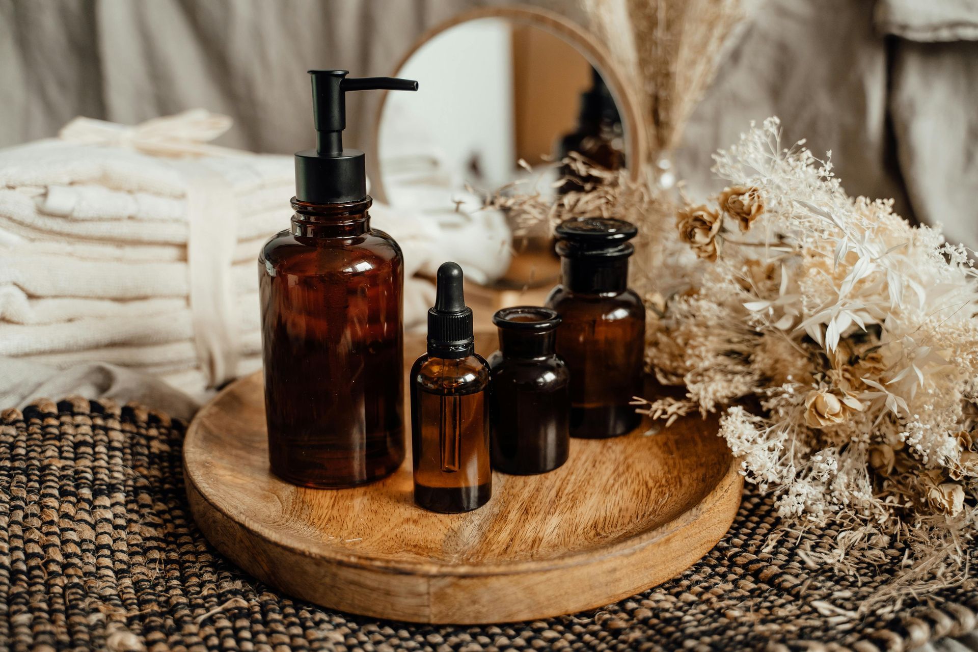 A wooden tray with bottles of essential oils and dried flowers on it.