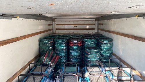The inside of a truck filled with lots of bags and carts.