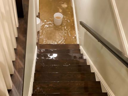A staircase with a bucket of water on the floor
