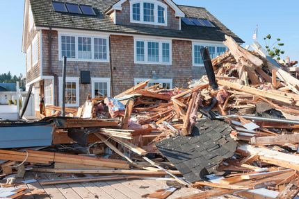 Rubble of a demolished house in front of another new house