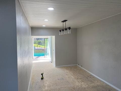 An empty room with a chandelier hanging from the ceiling.