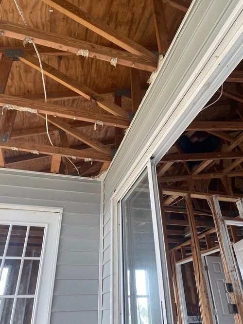 A house under construction with a sliding glass door and wooden beams.