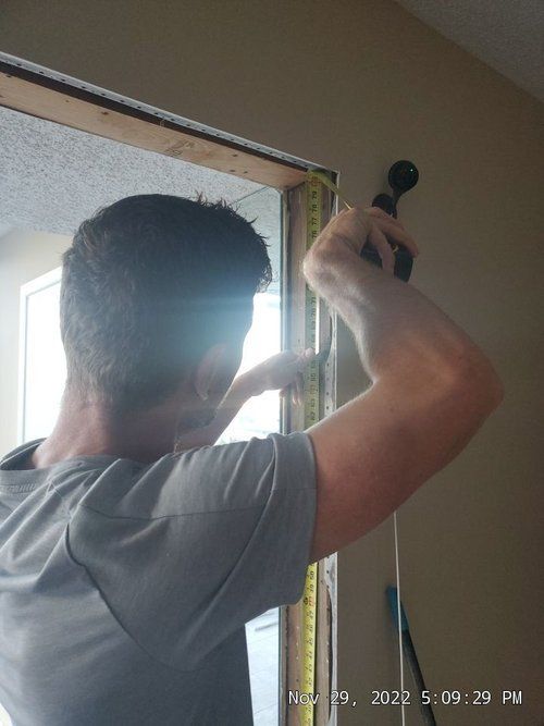 A man is measuring a door with a tape measure.