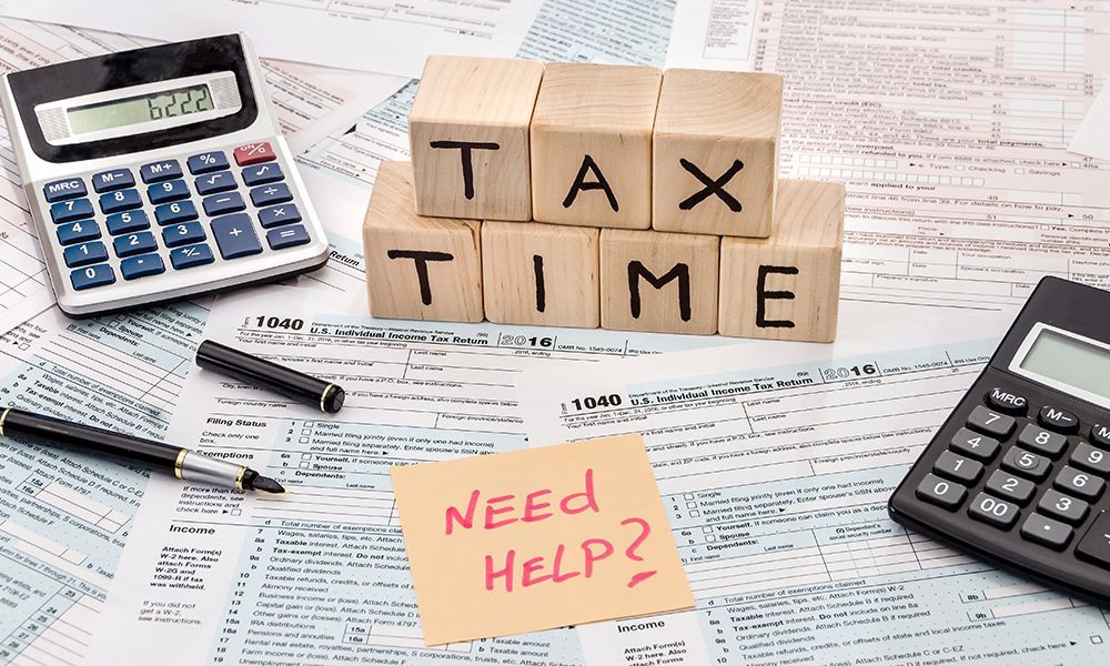 a calculator , pen , and a note that says `` tax time need help '' are on a table .