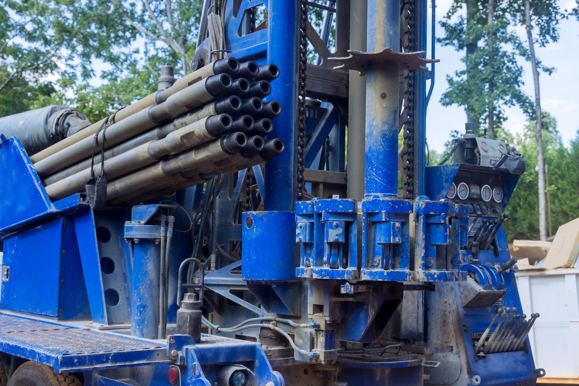 Blue drilling rig with multiple pipes on site.