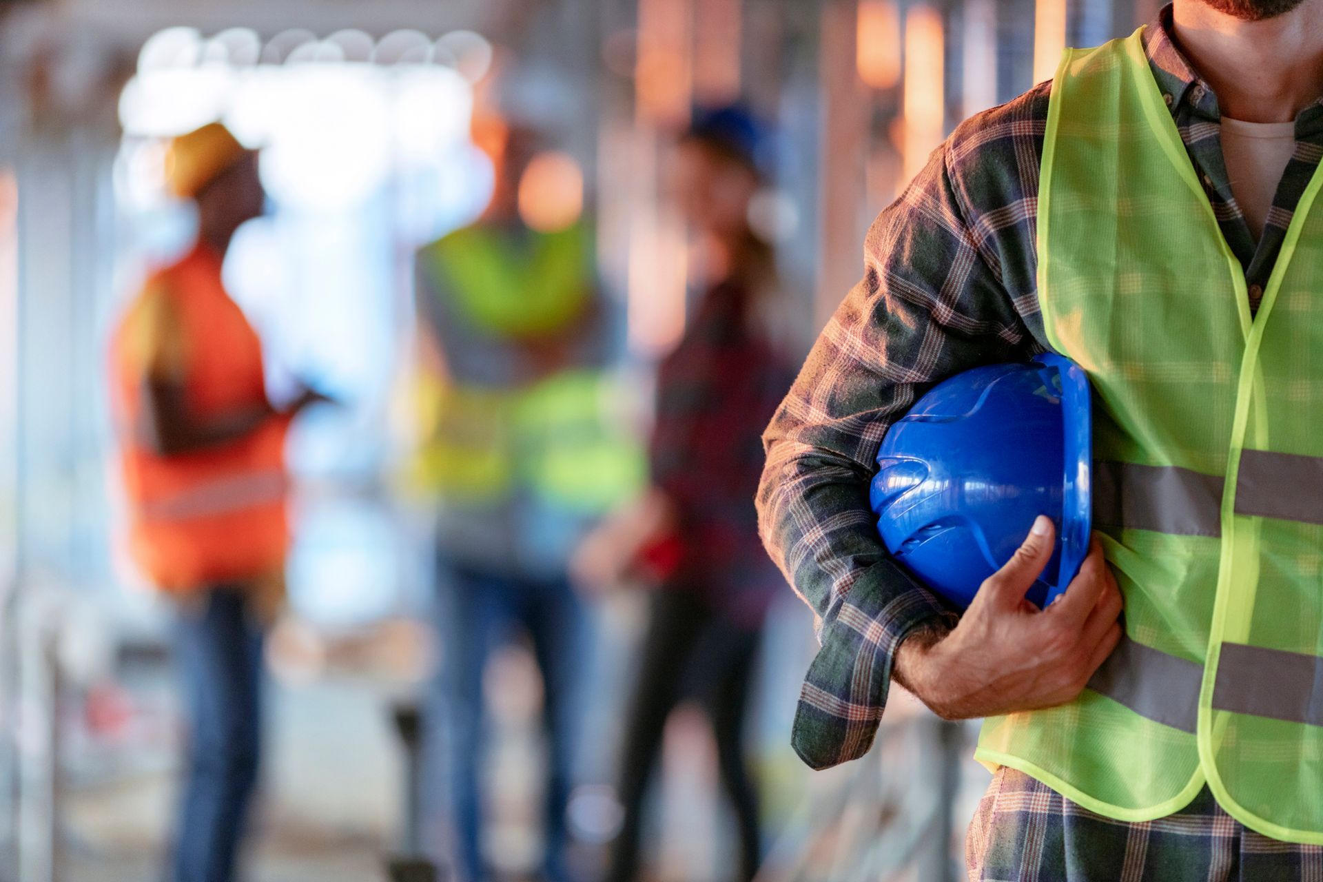 A man holding a blue helmet and other workers, showcasing commercial general contractor services.