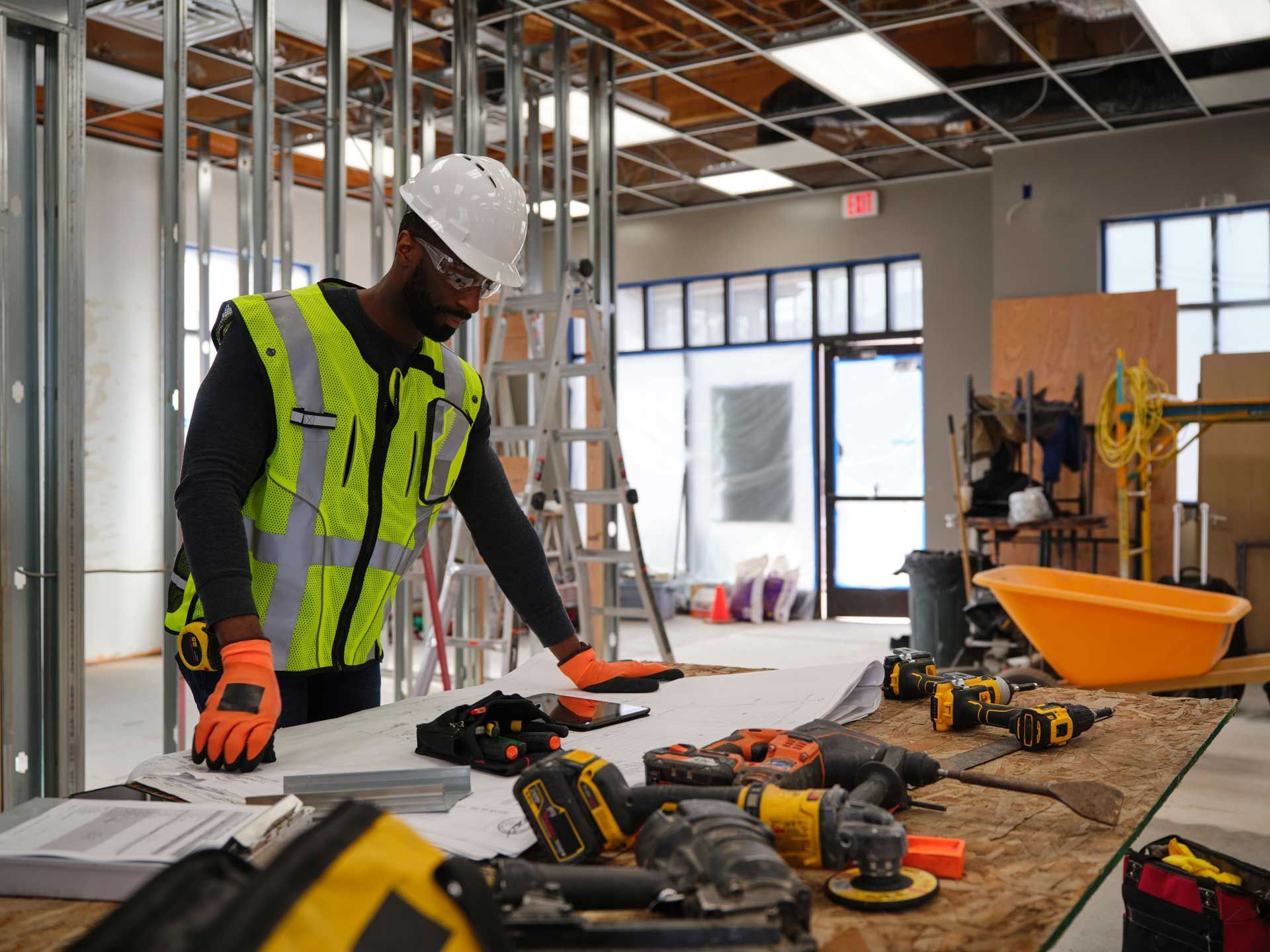 Construction worker with tools in a building, showcasing skills of a commercial general contractor.