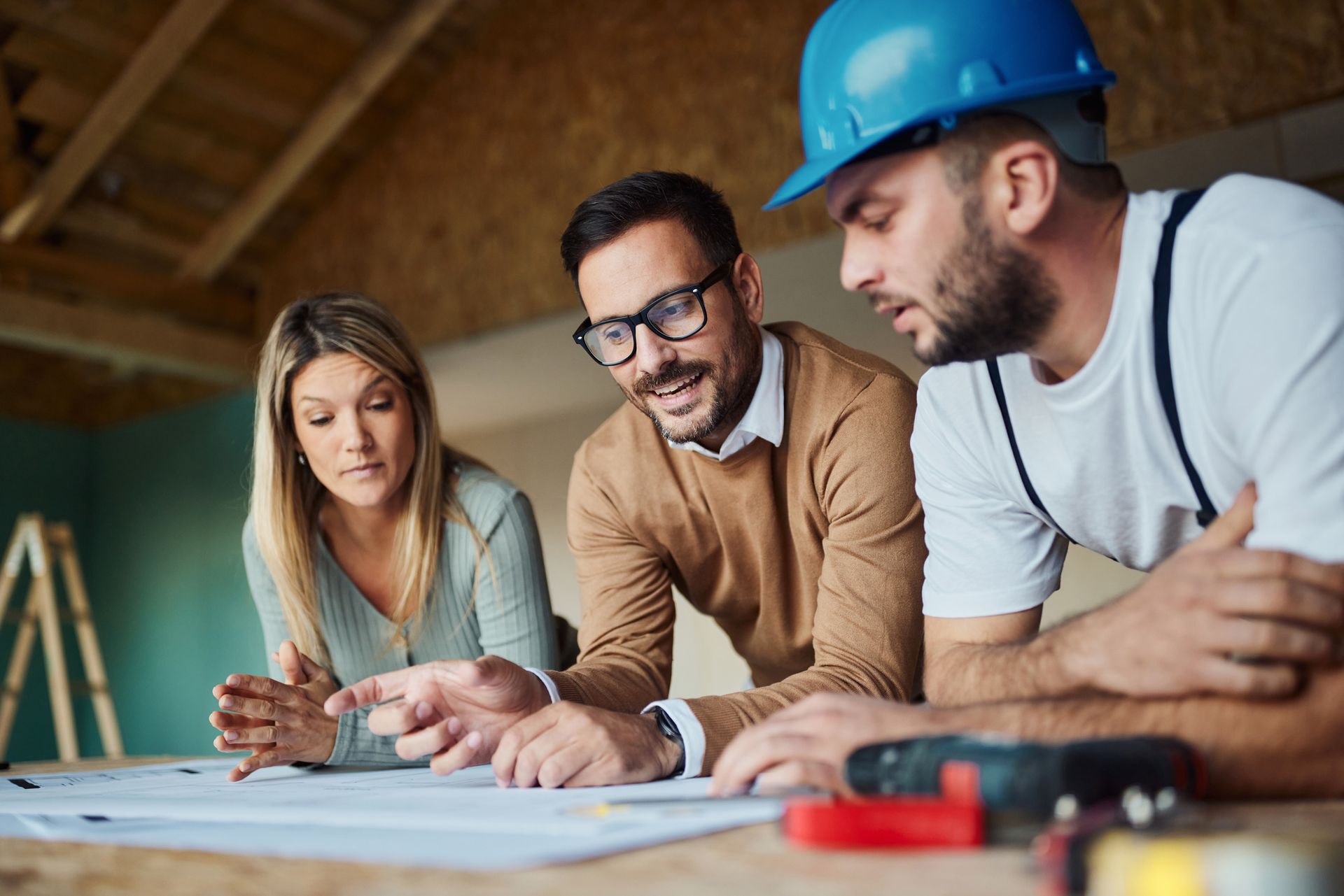 A couple and a home remodeling contractor examining blueprints. A couple and a home remodeling contractor examining blueprints.