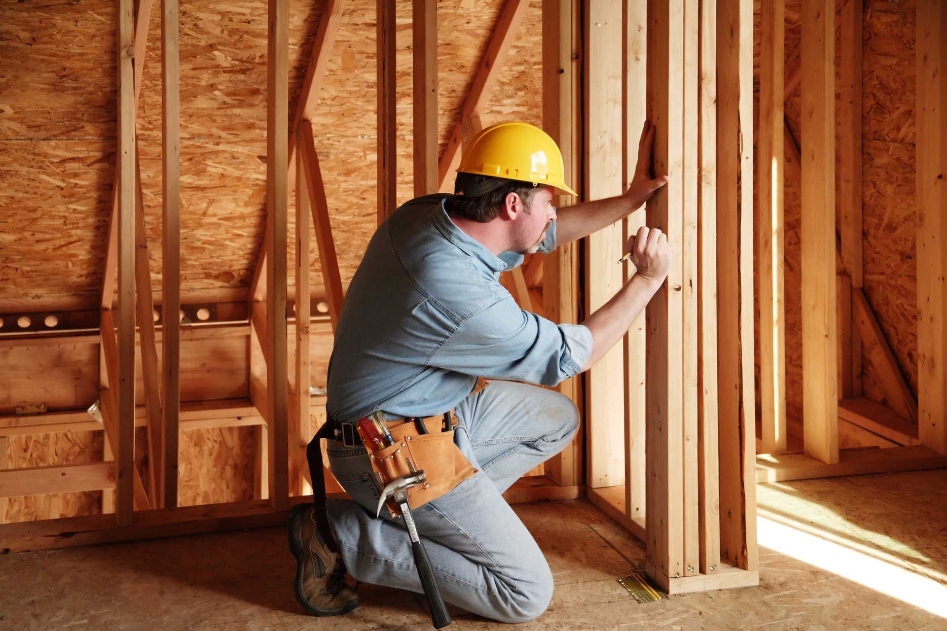 A man with a hammer at a construction site, showcasing skills as a commercial general contractor.