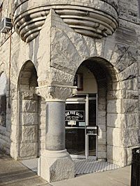 A stone building with arches and columns and a door.