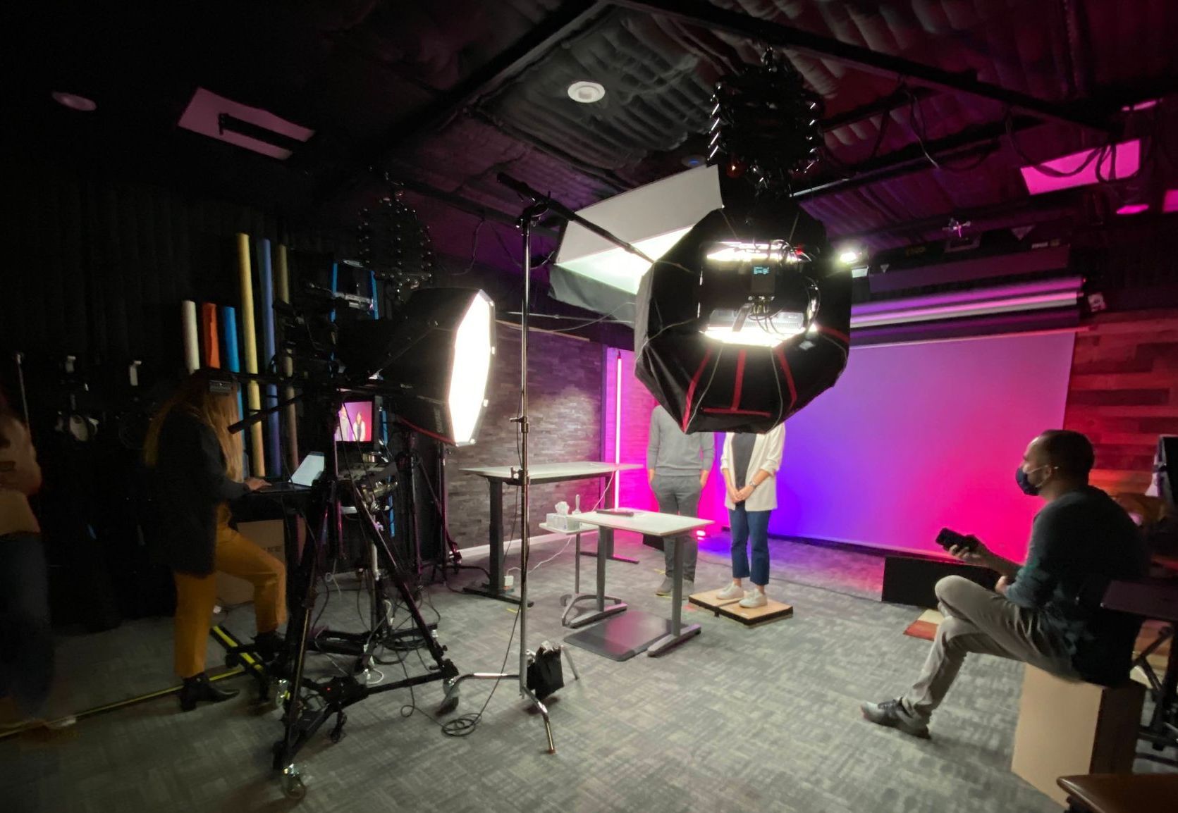A man is sitting on a cube in a studio with a camera.