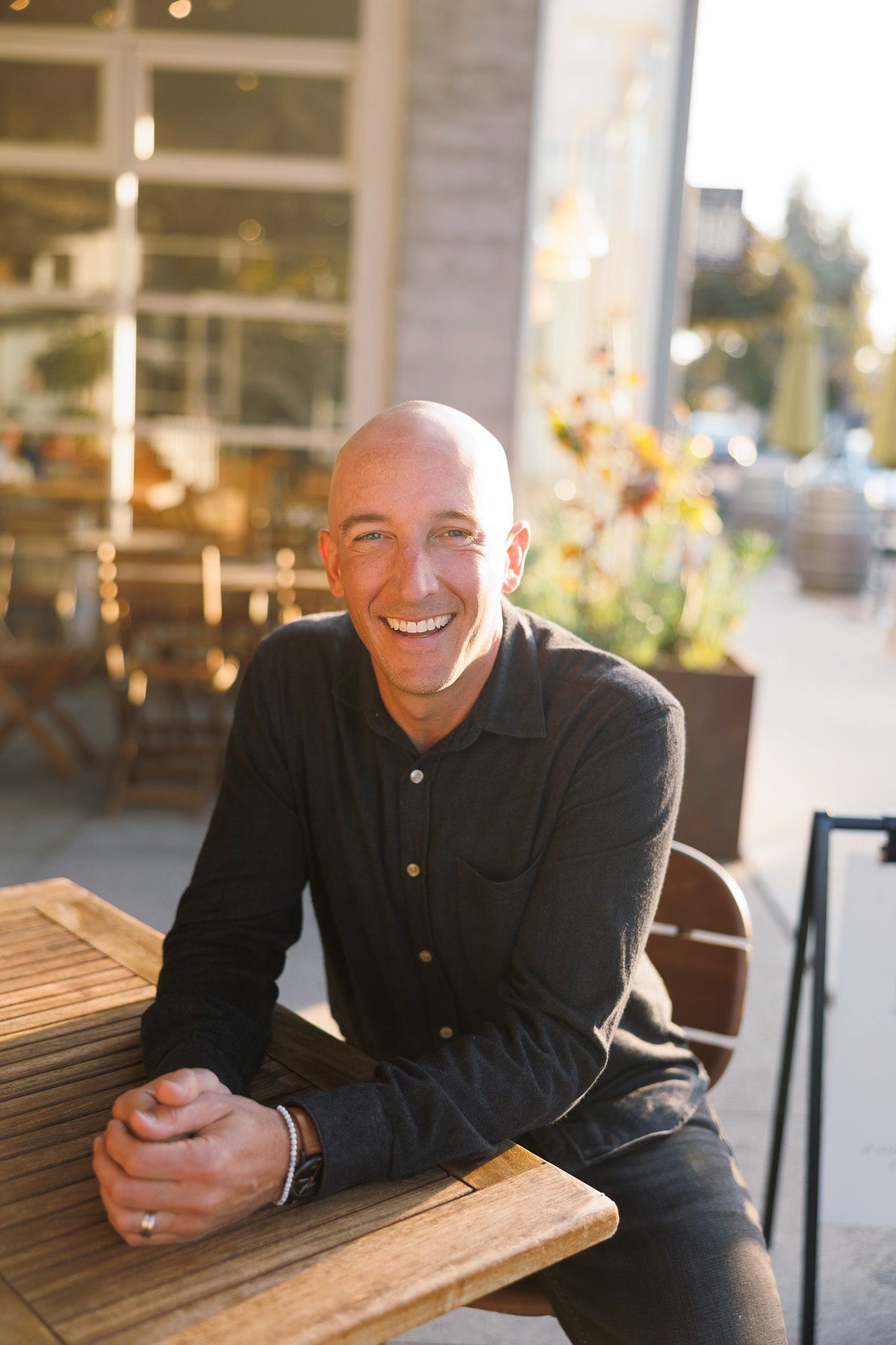 Greg Pickard is sitting at a table with his hands folded and smiling.