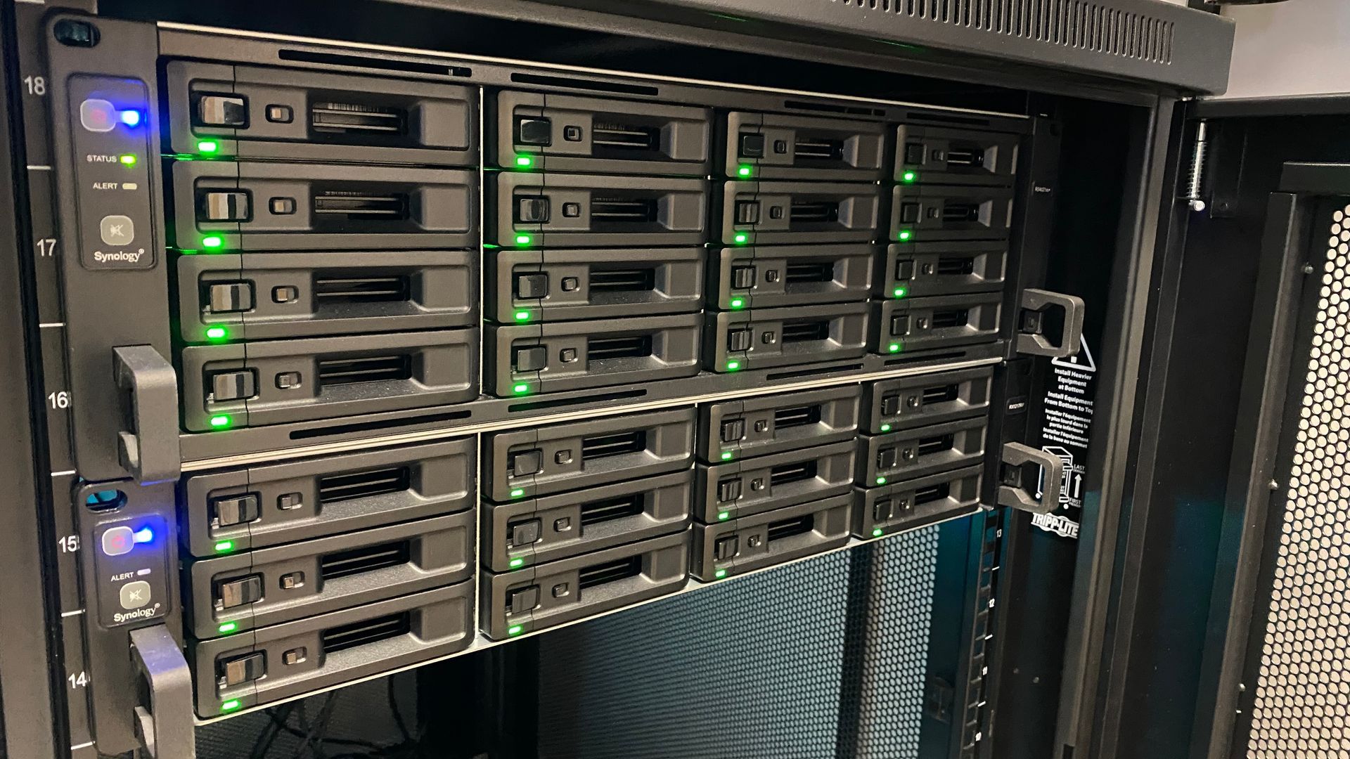 A server rack with lots of hard drives and green lights on it.