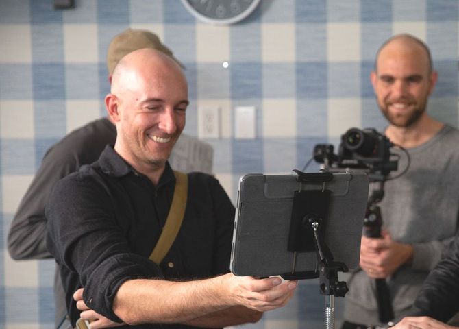 Greg Pickard is sitting on a chair and smiling.