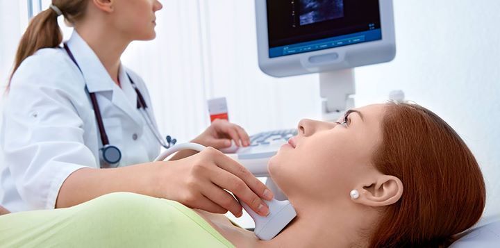 Un operatore sanitario esegue un'ecografia del collo su un paziente utilizzando una sonda portatile e un monitor digitale.