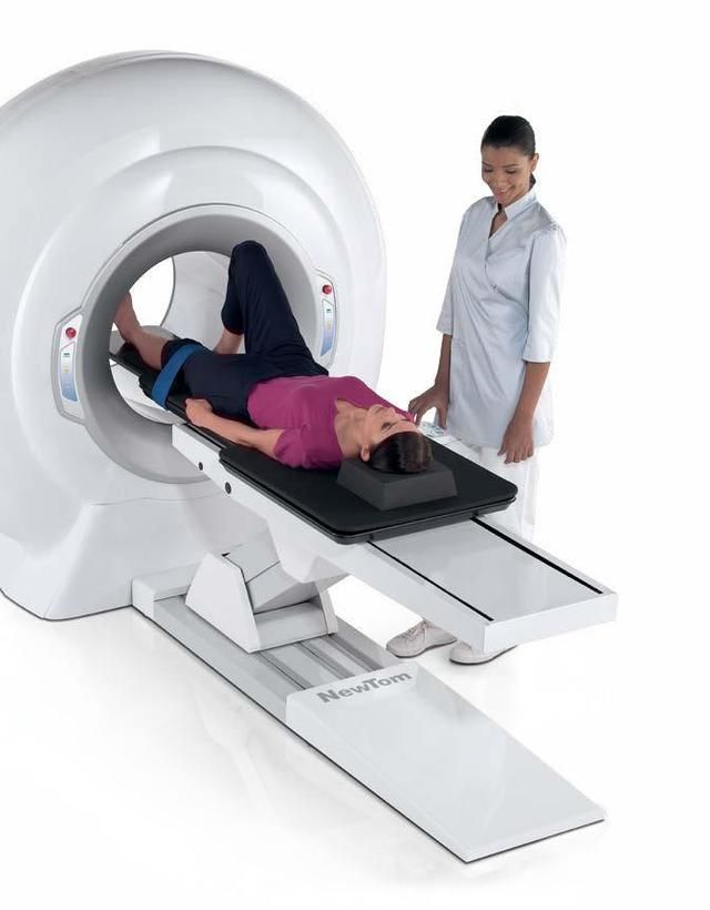 Un operatore sanitario osserva un paziente sdraiato sul lettino di uno scanner per immagini.