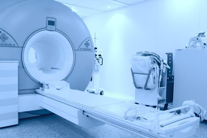Una sala clinica dai toni azzurri, dotata di una grande macchina per la risonanza magnetica con un lettino per il paziente che si estende all'interno dello scanner.