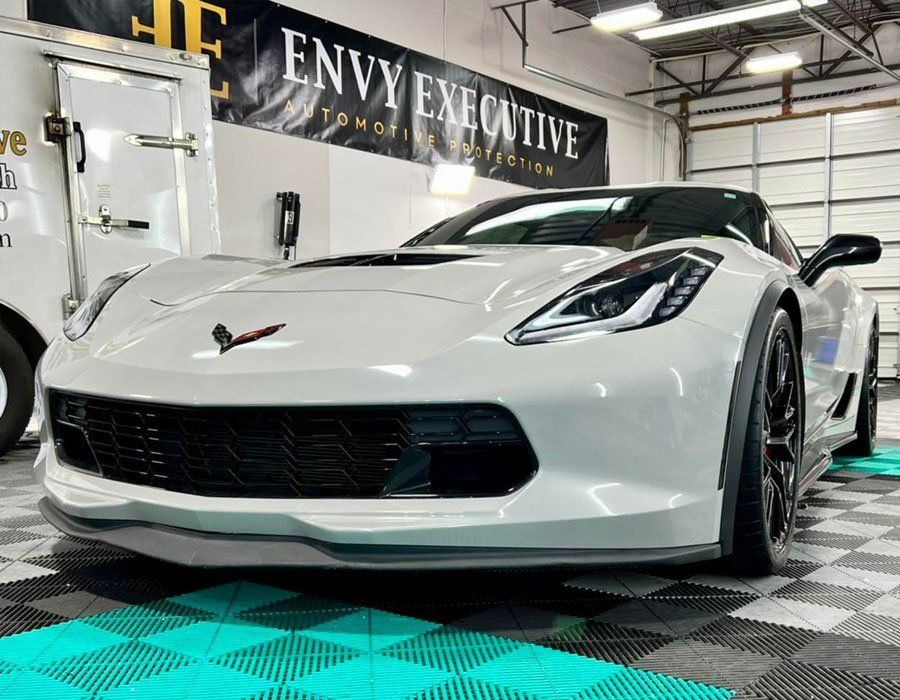 A white sports car is parked in a garage under a sign that says envy executive.