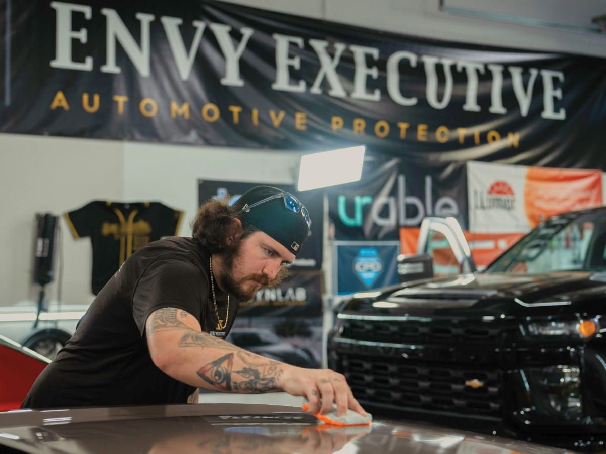 Detailing technician wiping a vehicle inside Envy Executive Automotive Protection.