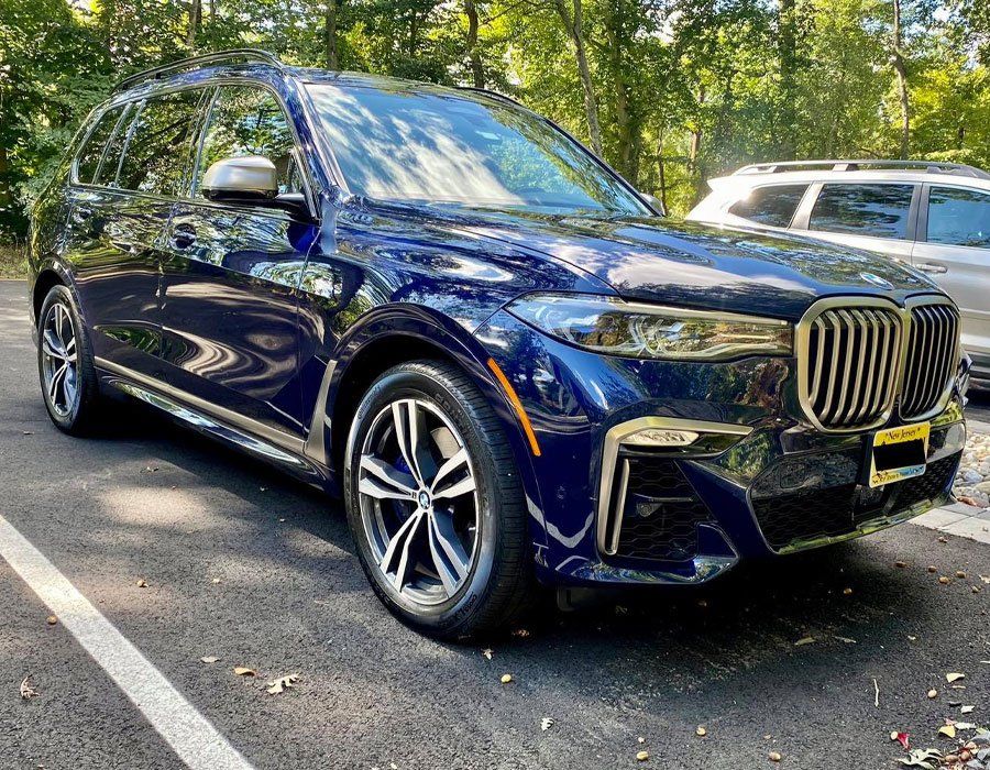A blue bmw x7 is parked in a parking lot.