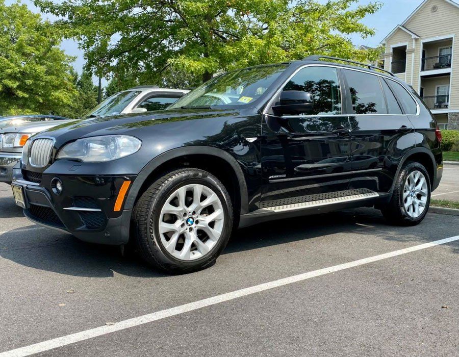 A black bmw x5 is parked in a parking lot.