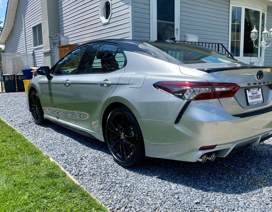 A silver toyota camry is parked in front of a house.