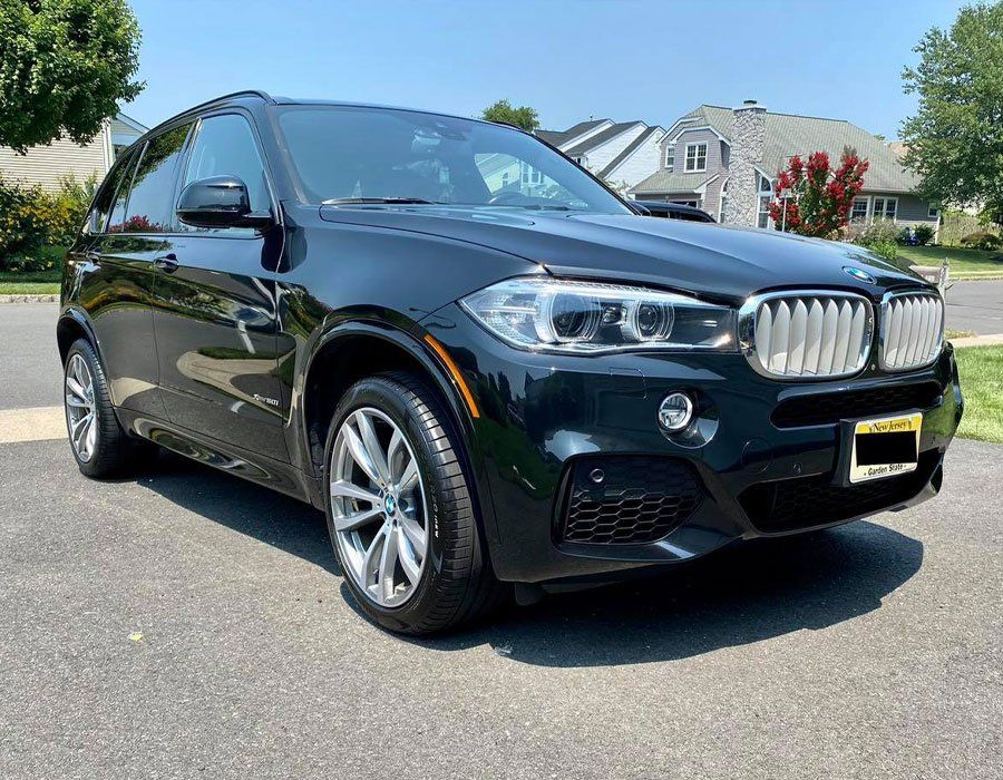 A black bmw x6 is parked on the side of the road.