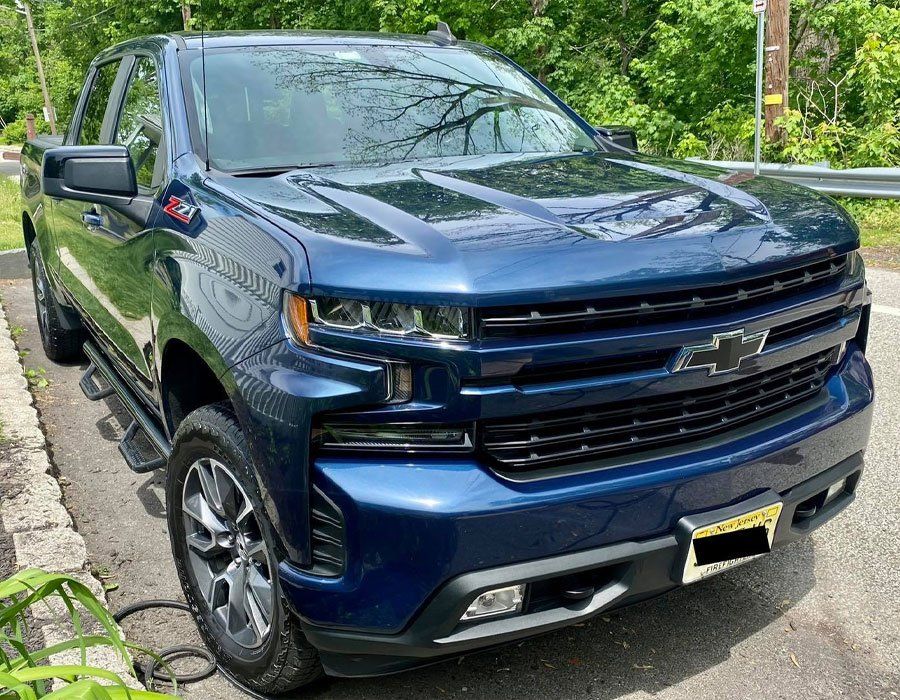 A blue chevrolet silverado truck is parked on the side of the road.