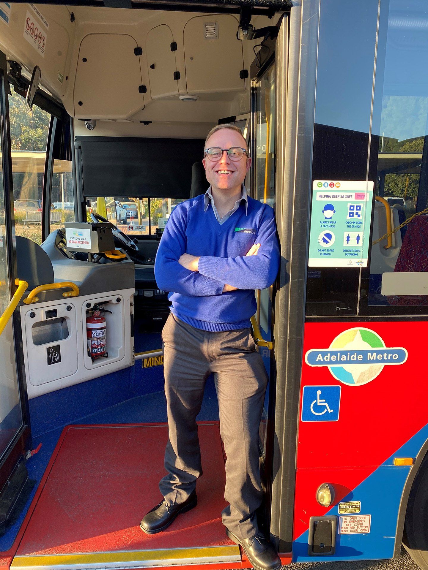 Photo of driver standing in buses doorway.