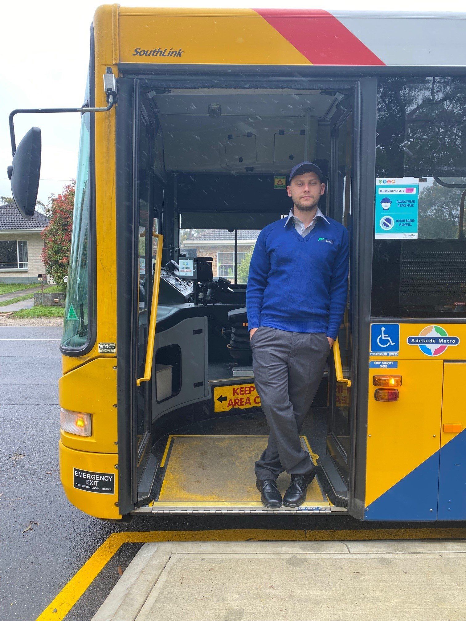 Photo of driver standing in buses doorway.