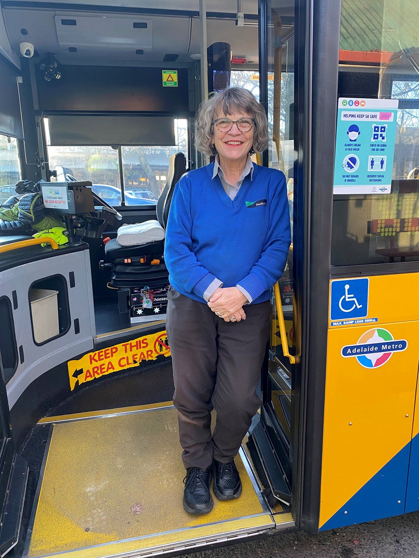 Photo of woman driver standing in buses doorway.
