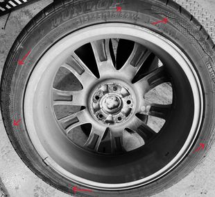 Close-up of a tire with multiple cracks. The tire is mounted on a silver alloy wheel.
