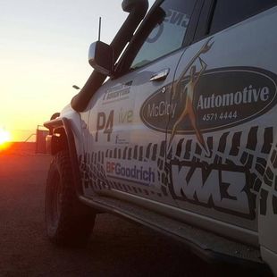 Off-road vehicle with sponsor logos, including BFGoodrich, at sunset.