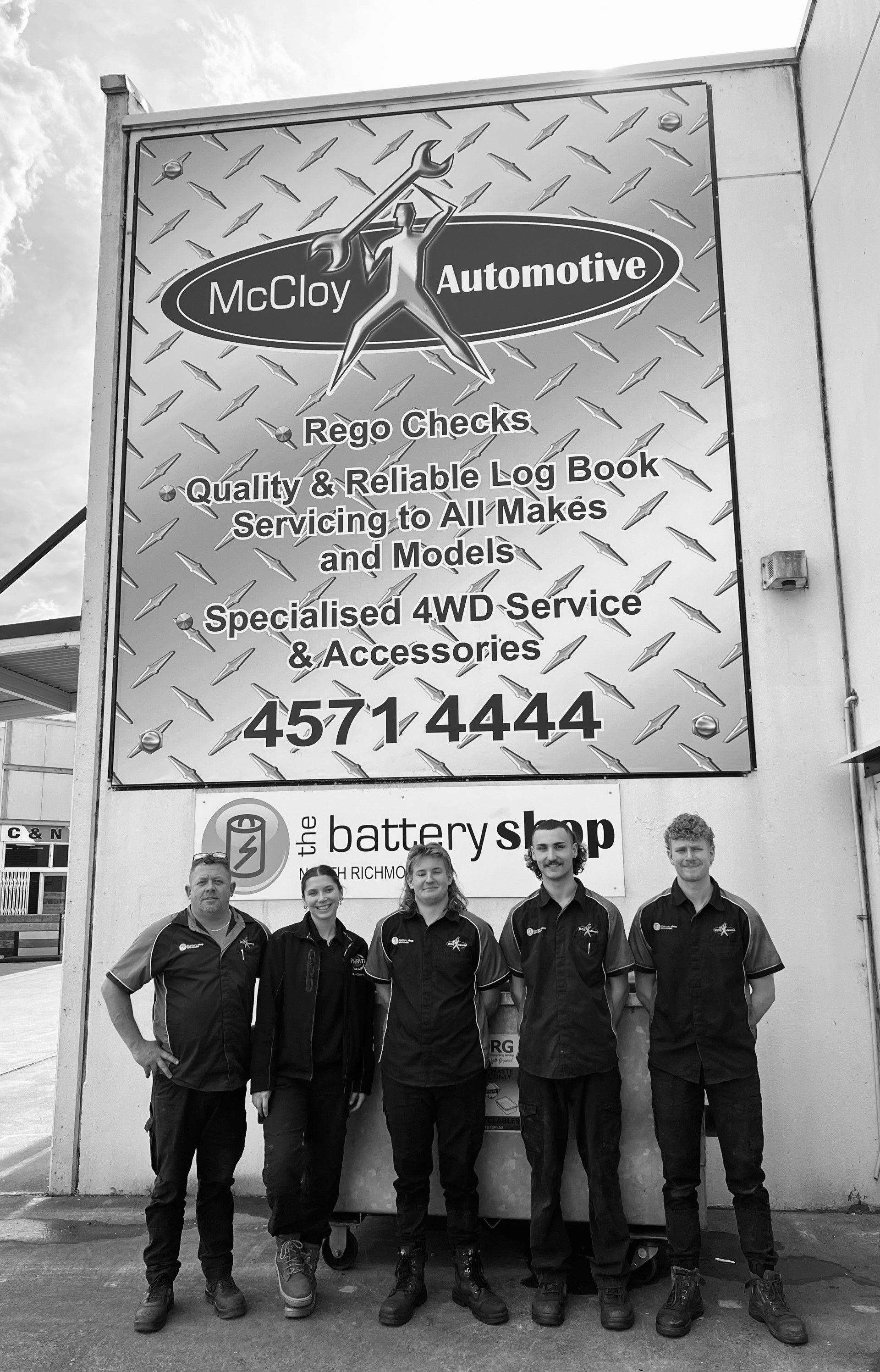 Five auto shop employees stand in front of a sign for McClay Automotive.