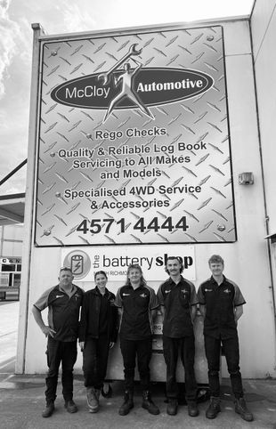 Five auto shop employees stand in front of a sign for McClay Automotive.