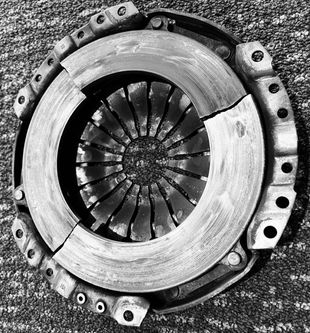 Broken clutch assembly, a circular automotive part with a center diaphragm and cracked outer ring.